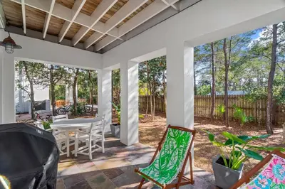a porch with chairs and a table and a fence at Ocean Serenade in Rosemary Beach