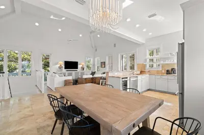 a large white kitchen with a wooden table and chairs at Ocean Serenade in Rosemary Beach