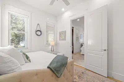 a white bedroom with a bed and a window at Ocean Serenade in Rosemary Beach
