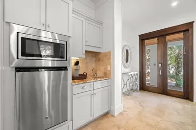 a kitchen with white cabinets and a stainless steel refrigerator at Ocean Serenade in Rosemary Beach