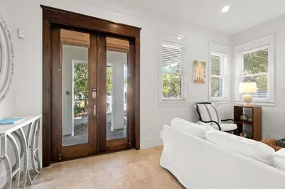 a living room with a white couch and a wooden door at Ocean Serenade in Rosemary Beach