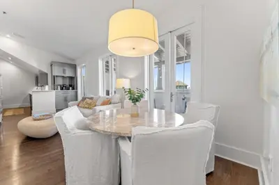 a dining room with a table and white chairs at The Savannah Unit 2E in Rosemary Beach