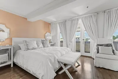 a white bedroom with a bed and a chair at The Savannah Unit 2E in Rosemary Beach