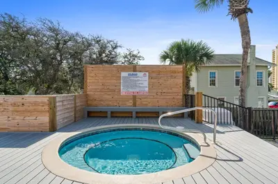 a hot tub on a deck with a bench and a sign at Portside Resort Pet Friendly Rentals by Panhandle Getaways in Panama City Beach