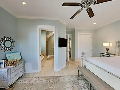 a bedroom with a ceiling fan and a living room at Seabreeze Cabana in Rosemary Beach