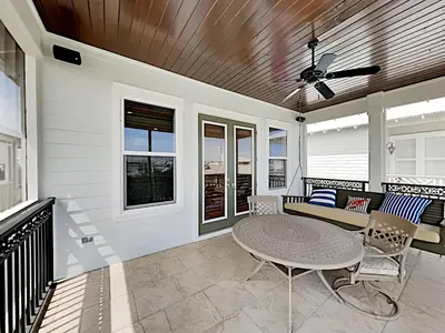 a screened in porch with a table and chairs at Seabreeze Cabana in Rosemary Beach