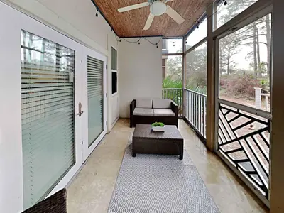 a screened in porch with a couch and a table at Seagrove Highlands #2104 in Santa Rosa Beach