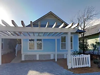 a blue house with a white pergola at The Good Life in Seacrest