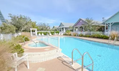 a large blue swimming pool with two white benches at The Good Life in Seacrest