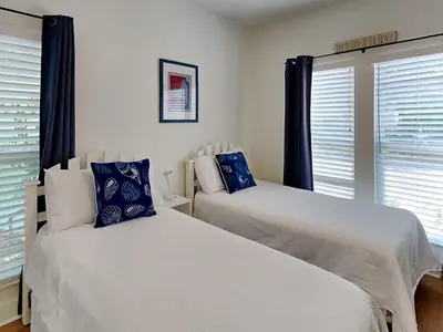 two white beds in a bedroom with windows at The Good Life in Seacrest