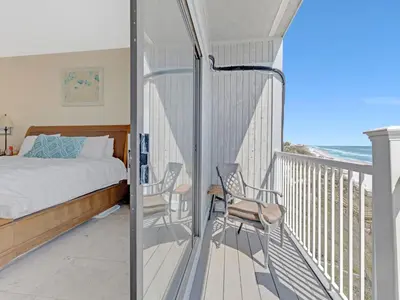 a bedroom with a bed and two chairs on a balcony at Seagrove Dunes #1 in Seagrove Beach