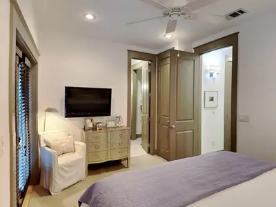 a bedroom with a bed and a flat screen tv at The Holland House II in Rosemary Beach