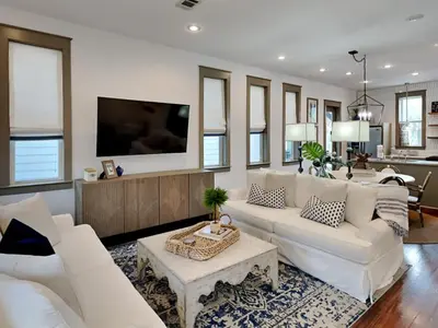 a living room with white furniture and a flat screen tv at The Holland House II in Rosemary Beach