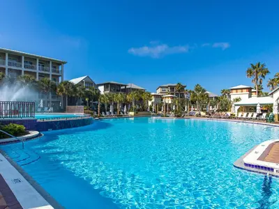 a large swimming pool at a resort with palm trees at The Holland House II in Rosemary Beach
