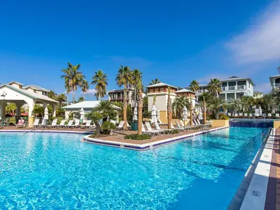 a pool at a resort with palm trees and houses at The Holland House II in Rosemary Beach