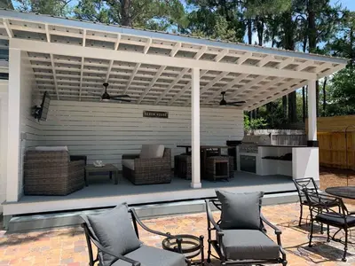 a pergola over a patio with chairs and a grill at Happy as a Clam in Santa Rosa Beach