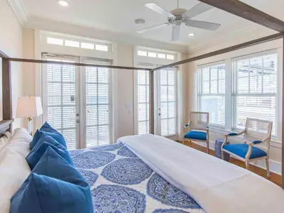 a bedroom with a bed and chairs and windows at All Decked Out 30A in Seagrove Beach