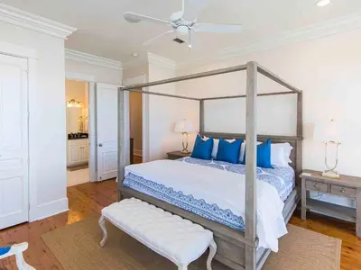 a bedroom with a canopy bed with blue pillows at All Decked Out 30A in Seagrove Beach