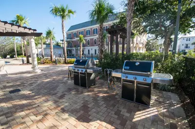 two bbqs and a grill in a courtyard with palm trees at Village Of South Walton #403E in Rosemary Beach