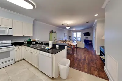 a kitchen with white cabinets and a living room at Village Of South Walton #403E in Rosemary Beach