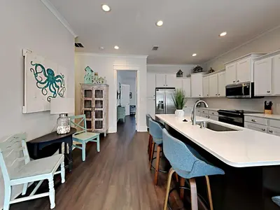 a kitchen with white cabinets and blue chairs at Casa Migos in Rosemary Beach
