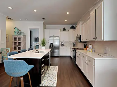 a kitchen with white cabinets and a sink and a counter at Casa Migos in Rosemary Beach