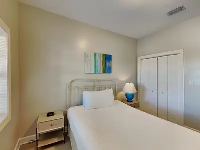a white bedroom with a bed and a nightstand with a lamp at Village Of South Walton #263A in Rosemary Beach