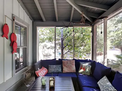 a blue couch in a screened in porch with a table at Sand Piper in Seacrest