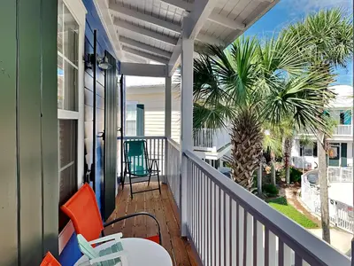 a porch with chairs and a table and a palm tree at Bungalows at Seagrove #147 in Seagrove Beach