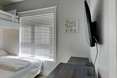 a bedroom with a bed and a window with a desk at Magnolia House in Seagrove Beach