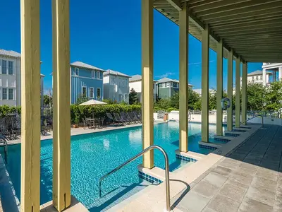 a swimming pool at a resort with tables and chairs at Magnolia House in Seagrove Beach