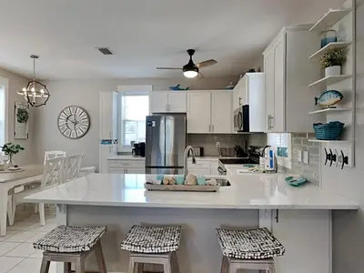 a kitchen with white cabinets and a large island with stools at Bungalows at Seagrove #138 in Seagrove Beach