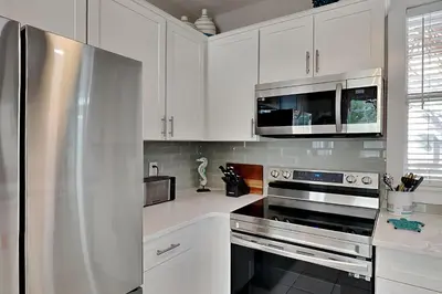 a kitchen with white cabinets and a stainless steel refrigerator at Bungalows at Seagrove #138 in Seagrove Beach
