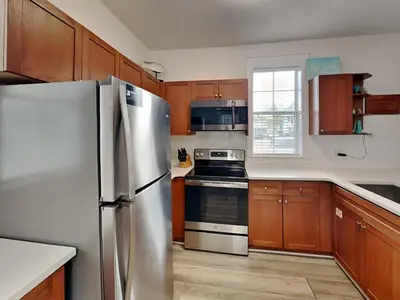 a kitchen with wooden cabinets and a stainless steel refrigerator at Bungalows at Seagrove #132 - Kruks Fanta Sea in Seagrove Beach