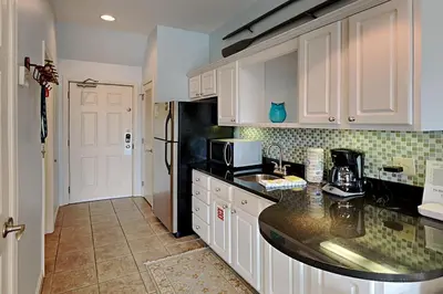 a kitchen with white cabinets and a black counter top at Inn at Seacrest #206 in Rosemary Beach