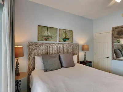 a bedroom with a white bed with two paintings on the wall at Inn at Seacrest #206 in Rosemary Beach