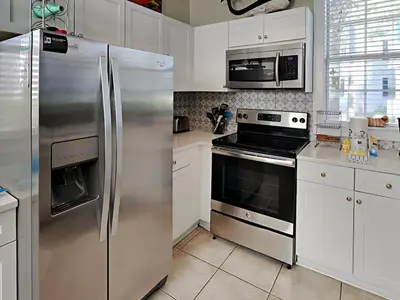a kitchen with stainless steel appliances and white cabinets at Bungalows at Seagrove #142 in Seagrove Beach