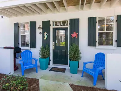 two blue chairs sitting on the front porch of a house at Bungalows at Seagrove #142 in Seagrove Beach