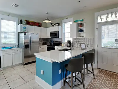 a kitchen with white cabinets and a blue island at Bungalows at Seagrove #142 in Seagrove Beach