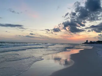 a sunset on the beach with the ocean at Beachside Villas #413 in Seagrove Beach