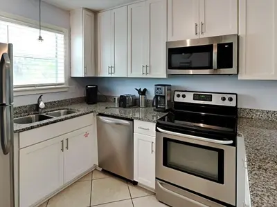 a kitchen with stainless steel appliances and white cabinets at Beachside Villas #413 in Seagrove Beach