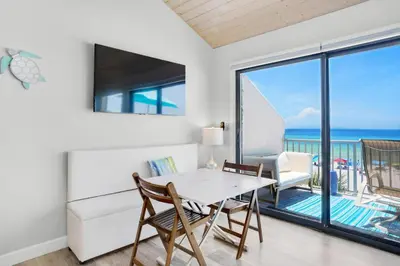 a dining room with a table and chairs and a view of the ocean at Nautical Watch A-11 in Panama City Beach