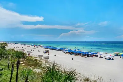 a beach with umbrellas and chairs and the ocean at Nautical Watch A-11 in Panama City Beach