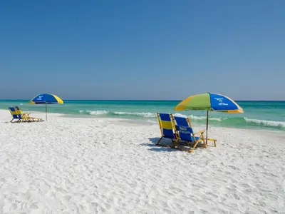 two lawn chairs and umbrellas on a beach at Legacy 506- The Coastal Gem in Santa Rosa Beach