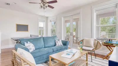 a living room with a blue couch and a table at Chic 30A Beach Home Views Ping Pong 5-Min Walk to Carillon Beach Bellview in Sunnyside