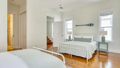two beds in a bedroom with white walls and wood floors at Chic 30A Beach Home Views Ping Pong 5-Min Walk to Carillon Beach Bellview in Sunnyside