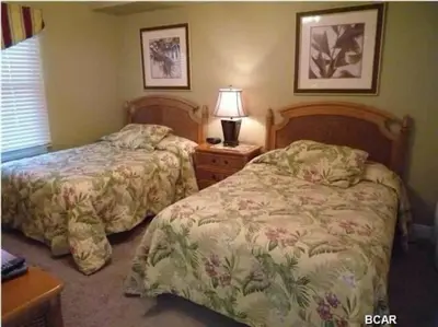 a bedroom with two beds and a lamp on a table at Celadon Beach Resort in Panama City Beach