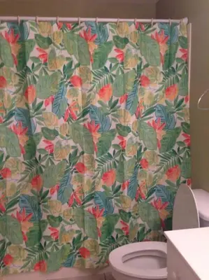 a bathroom with a floral shower curtain with a toilet at Celadon Beach Resort in Panama City Beach