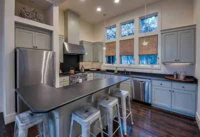 a kitchen with a large counter with stools in it at Zen Den Cottage in Rosemary Beach