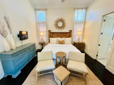 a bedroom with a bed and two chairs and a table at Zen Den Cottage in Rosemary Beach